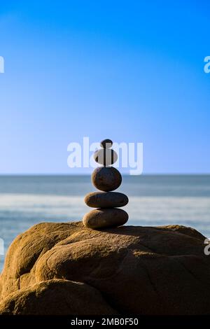 A well-balanced cairn on the beach of the small town of Castle di Tusa, symbol of spirituality and balance, the waters of the sea behind. Stock Photo