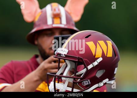 FILE - Washington Commanders helmets with Guardian Caps sit on the field  during practice at the team's NFL football training facility, Saturday,  July 30, 2022 in Ashburn, Va. The mushroom-like contraptions NFL