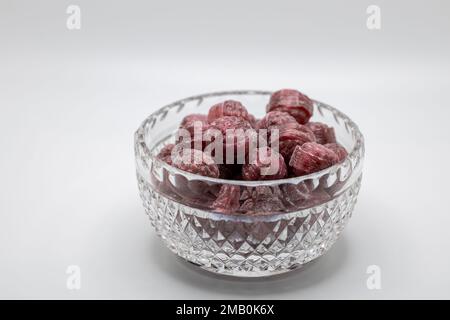 Macro view of a small beautiful vintage lead crystal bowl containing hard raspberry candies, on white background with copy space Stock Photo