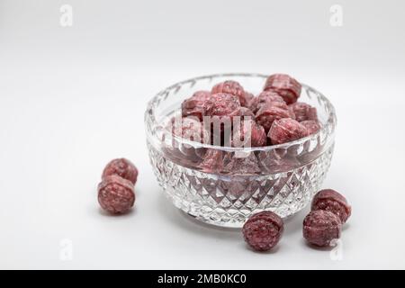 Macro view of a small beautiful vintage lead crystal bowl containing hard raspberry candies, on white background with copy space Stock Photo
