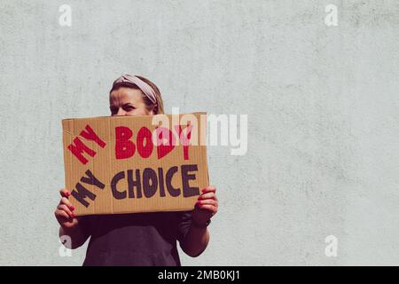 Woman holding placard sign with slogan My Body My Choice during manifestation. Female protester with banner at protest rally demonstration. Stock Photo