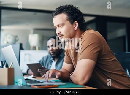 Busy with my business. a young businessman using a laptop in an office. Stock Photo