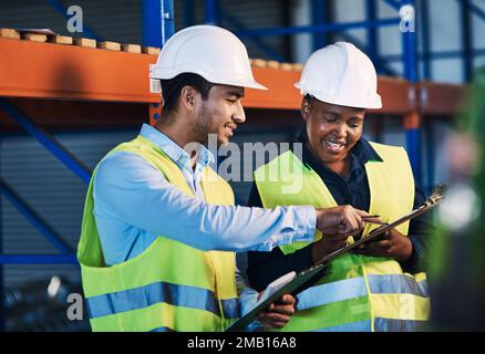 Can we order more of these. two young contractors standing in the warehouse and having a discussion while doing a stock-take. Stock Photo