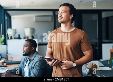Thinking of all my business plans. a young businessman using a digital tablet in an office. Stock Photo