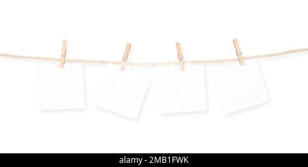 Four blank square notepads reminders and clothespins attached to a rope isolated on white background. Clipping Path Included. Stock Photo