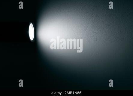 Spotlight, lamp with beam of light on the wall in dark room Stock Photo
