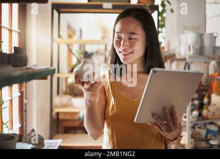 Creative asian woman, tablet and smile for pottery business, checking inventory or pricing at workshop. Happy Japanese female smiling holding Stock Photo