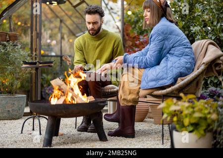 Young couple spending dinner time by the fire at backyard Stock Photo