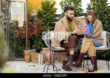 Couple sit covered with plaid in garden Stock Photo