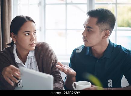 What are we going to do about this. a young couple using a digital tablet together at home. Stock Photo