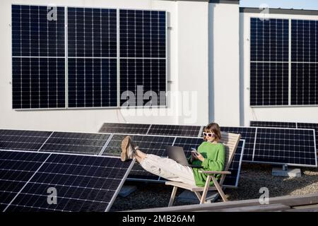 Woman works on a rooftop with a solar station Stock Photo