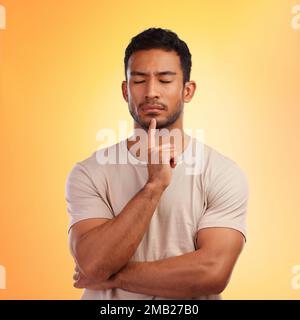 Thinking, meditate and man in studio to focus, remember memory or decision on yellow background. Face of model person with hand on chin and eyes Stock Photo