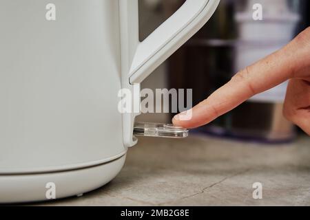 Close up of person turning on power button on electric kettle Stock Photo