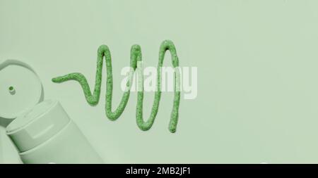 Creamy natural scrub on green background. Mock up. Liquid cosmetic, poured texture from a tube Stock Photo