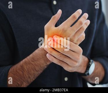 My wrists cant take the endless typing. an unrecognizable businessman standing alone in his office and suffering from carpal tunnel. Stock Photo