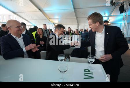 20 January 2023, Schleswig-Holstein, Brunsbüttel: Robert Habeck (M, Bündnis 90/Die Grünen), Federal Minister for Economic Affairs and Climate Protection, and Daniel Günther (r, CDU), Minister President of Schleswig-Holstein, and Tobias Goldschmidt (Bündnis 90/Die Grünen), Schleswig-Holstein's Minister for Energy Transition, Climate Protection, Environment and Nature, talk during the ceremony in Elbehafen to mark the arrival of the floating LNG terminal. At the floating LNG terminal 'Höegh Gannet', liquefied natural gas is processed for transport in pipelines. Brunsbüttel is the third LNG termi Stock Photo