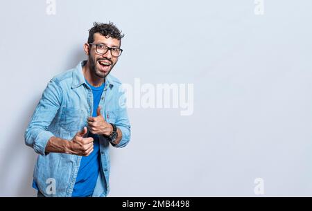 Handsome man with thumbs up doing ok, young man with thumbs up on white background, Smiling man showing ok gesture looking at camera Stock Photo