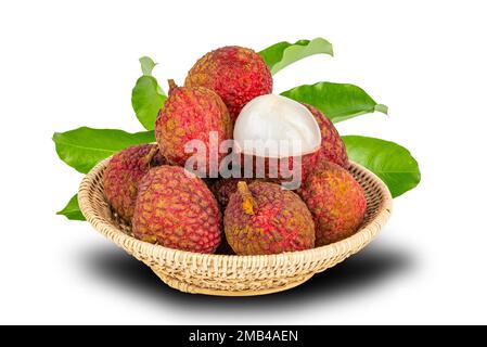 Pile of ripe lychee with green leaves in bamboo basket isolated on white background with clipping path Stock Photo