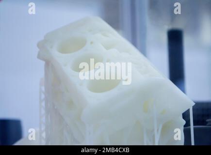 Object printed on 3D printer from plastic. The object a prototype of an automobile engine printed on a 3D printer from white plastic. 3D volumetric model. Concept new modern printing technology Stock Photo