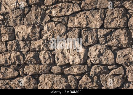 Closeup of wall made of hewn rocks lit with sunlight Stock Photo