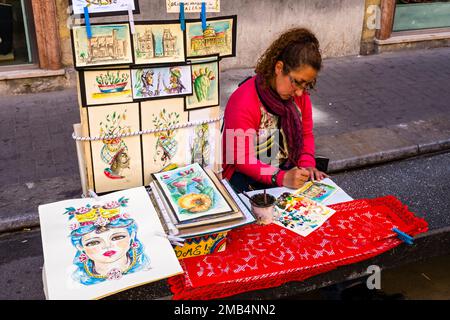 A femal artist is painting colorful paintings in the streets of one of the Palermo suburbs. Stock Photo