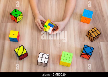 Khabarovsk, Russia, February 18, 2022. Top view male adolescent hands assembling Rubik's cubes 3x3, axis, 2x2, 4x4, skyube, mirror mill Stock Photo