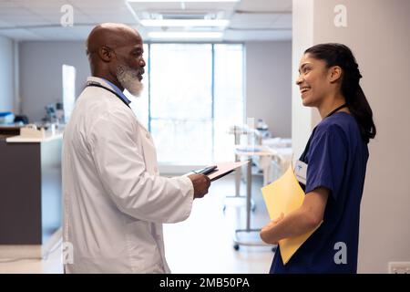 Happy diverse female and senior male doctor talking in hospital ward, copy space Stock Photo