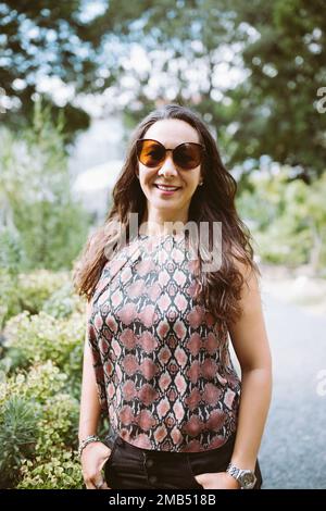 Beautiful young happy multiracial Japanese woman in jeans and shirt in summer park, smiling Stock Photo