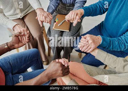 High angle view of group of senior people holding hands together with psychologist and supporting each other at session Stock Photo