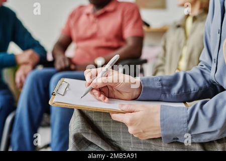 Close-up of psychologist making notes in document while working with people at session Stock Photo