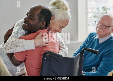 Senior woman embracing man with disability, they using hugging therapy Stock Photo