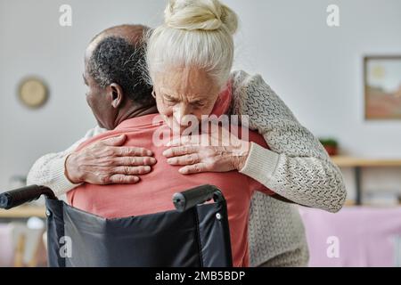 Senior woman embracing man with disability during hugging therapy Stock Photo