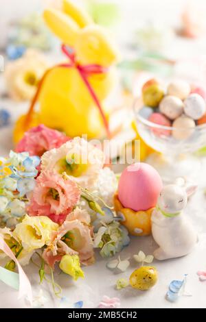 Happy Easter background with colorful eggs, candy and bunch of flowers. Table decorating for holiday. Stock Photo