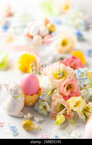 Happy Easter background with colorful eggs, candy and bunch of flowers. Table decorating for holiday. Stock Photo