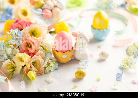 Happy Easter background with colorful eggs, candy and bunch of flowers. Table decorating for holiday. Stock Photo