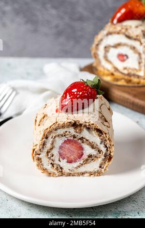 Strawberry Roll Cake. Log cake with cream and strawberries on a stone background. close up Stock Photo