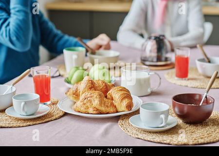 Close-up of senior people having breakfast with tea and croissants at table in kitchen Stock Photo