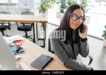 Smiling asian designer talking on smartphone in studio,stock image Stock Photo