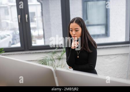 Concentrated asian designer looking at computer monitor in office,stock image Stock Photo