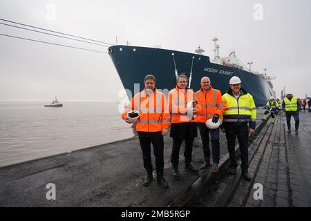 20 January 2023, Schleswig-Holstein, Brunsbüttel: Robert Habeck (l-r, Bündnis 90/Die Grünen), Federal Minister for Economic Affairs and Climate Protection, Daniel Günther (CDU), Minister President of Schleswig-Holstein, Tobias Goldschmidt (Bündnis 90/Die Grünen), Schleswig-Holstein's Minister for Energy Transition, Climate Protection, Environment and Nature, and Frank Schnabel, Managing Director of Brunsbüttel Ports GmbH, stand in front of the floating LNG terminal after the ceremony in the Elbehafen. At the floating LNG terminal 'Höegh Gannet', liquid natural gas is processed for transport in Stock Photo