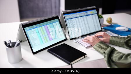 Businesswoman's Hand Examining Spreadsheet On Laptop In Office Stock Photo