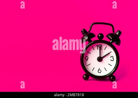 Alarm clock pointing at 2 am or pm with customizable space for text or ideas. Copy space with pink background. Stock Photo