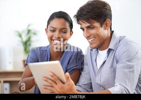 Check this out. two young colleagues using a digital tablet. Stock Photo