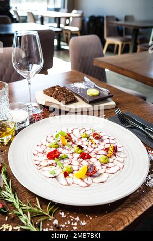 Octopus carpaccio. Spinach cream, cherry tomatoes. Delicious healthy Italian traditional food closeup served for lunch in modern gourmet cuisine Stock Photo