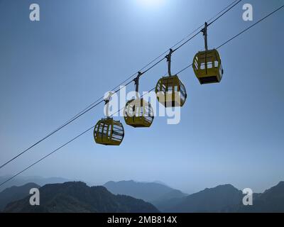 A low-angle of four yellow cable cars on the rope against a blue sky Stock Photo