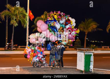 Nha Trang, Vietnam - 18 January 2023: Vietnamese sellers of balloons at night near road Stock Photo