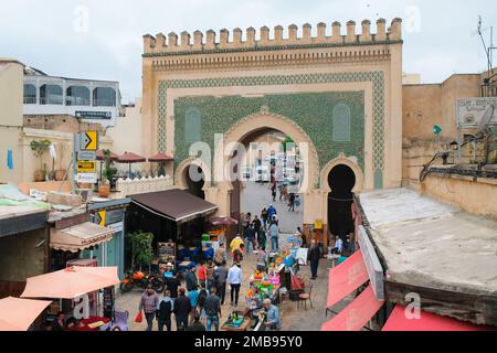 Fez, Morocco - grand city gate Bab Bou Jeloud from inside ancient Fes el Bali medina. Monumental French entrance. People on the street. Fes souk. Stock Photo