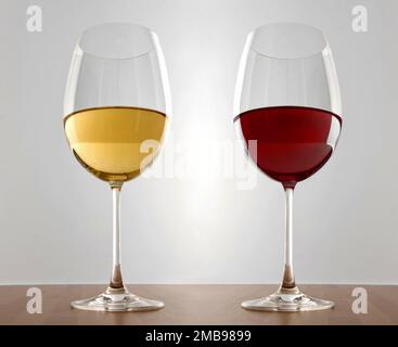 Glasses of white and red wine placed on wooden desk against gray background Stock Photo