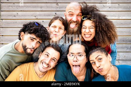 Young trendy friends taking selfie posing funny face expression - Happy life style concept with millenial people having fun together - University coll Stock Photo