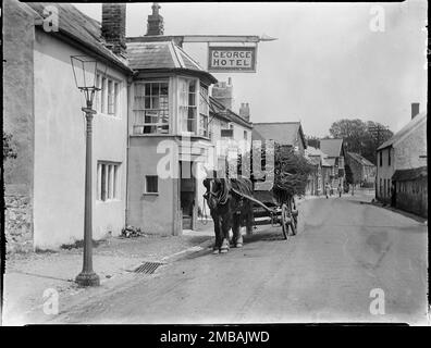 George Hotel, The Street, Charmouth, West Dorset, Dorset, 1925. A horse-drawn cart laden with faggots standing outside the George Hotel. The 'faggots' shown in the photograph are coppiced material consisting of branches and twigs bound together to form bundles of a certain length and diameter. Stock Photo